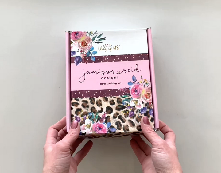 Female hands pick up and show in detail the contents of the "Jamison Reid" card making craft kit. 