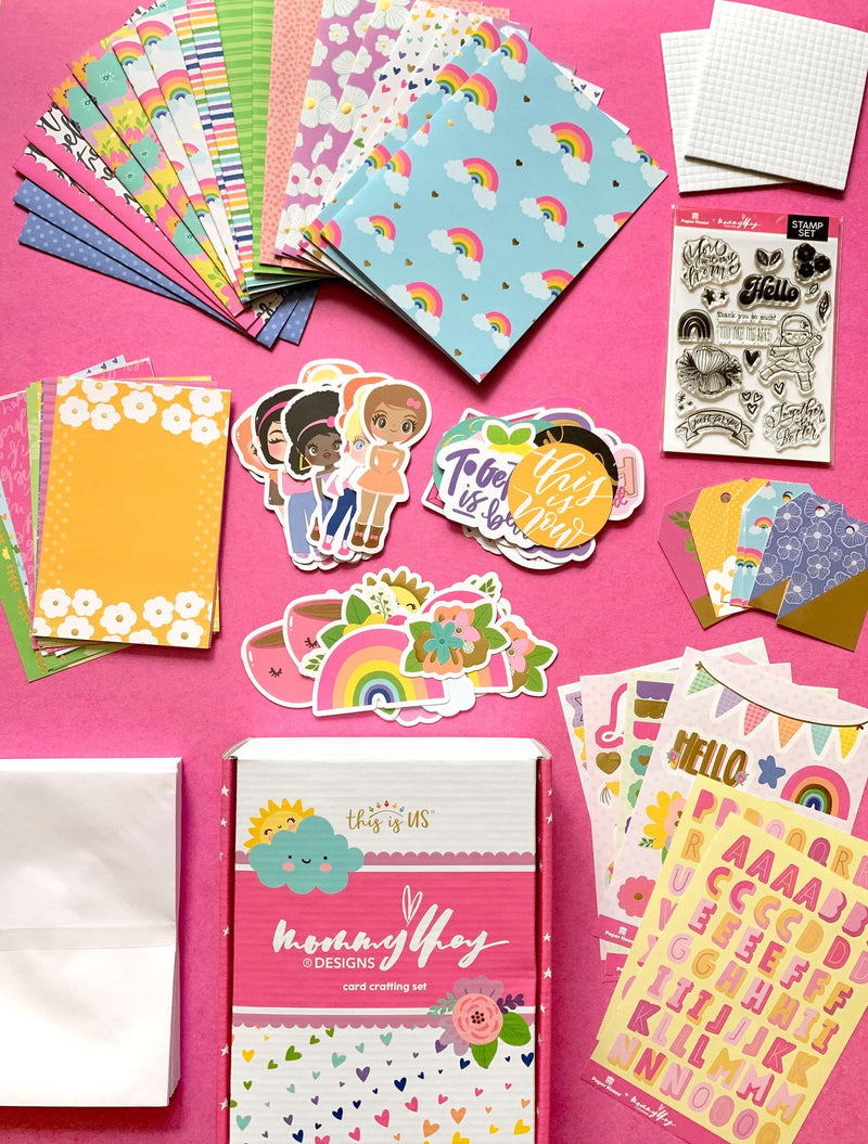 image shows full contents of the Mommy Lhey card making kit including paper, stickers, embellishments, stamps, and envelopes on a pink background