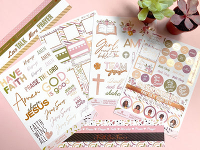 An assortment of stickers from this bible journaling craft kit are displayed  featuring soft, muted colors with gold details.
