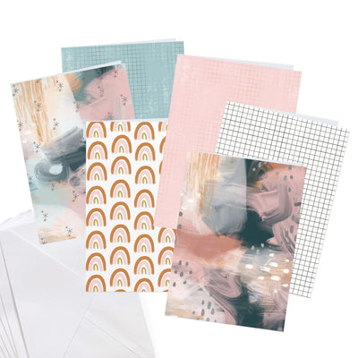 Six patterned craft kit cards featuring navy, gold and pink patterns are shown overlapping with white envelopes.  