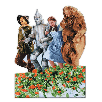 fridge magnet featuring the 4 characters from the Wizard of Oz, frolicking through the poppy field shown on a white background.