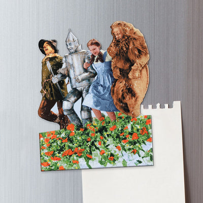 fridge magnet featuring the 4 characters from the Wizard of Oz, frolicking through the poppy field shown on a metal background attached to a torn memo sheet