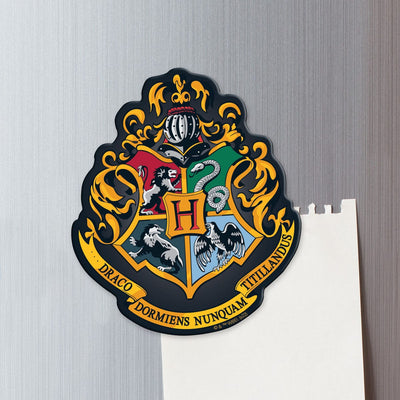 fridge magnet featuring a colorful Hogwarts crest shown on a metal background attached to a sheet of torn white memo paper.