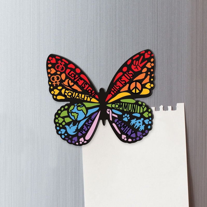 fridge magnet featuring a shaped butterfly with colorful words of love and diversity shown on a metal background attached to a torn sheet of white memo paper.