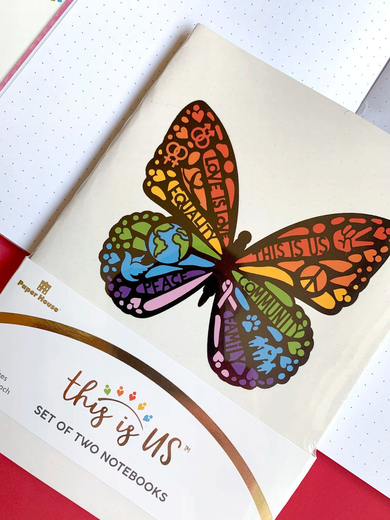 A rainbow colored butterfly featuring love, respect and diversity are depicted on the cover of this journal notebook. Shown in its package on top of an open spread of a dot grid page.