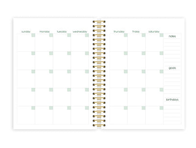 weekly planner featuring a monthly spread with gold coil spine, shown on white background.
