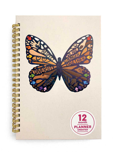 weekly planner featuring a large illustrated butterfly with words of unity, shown on a beige cover with a gold spine.