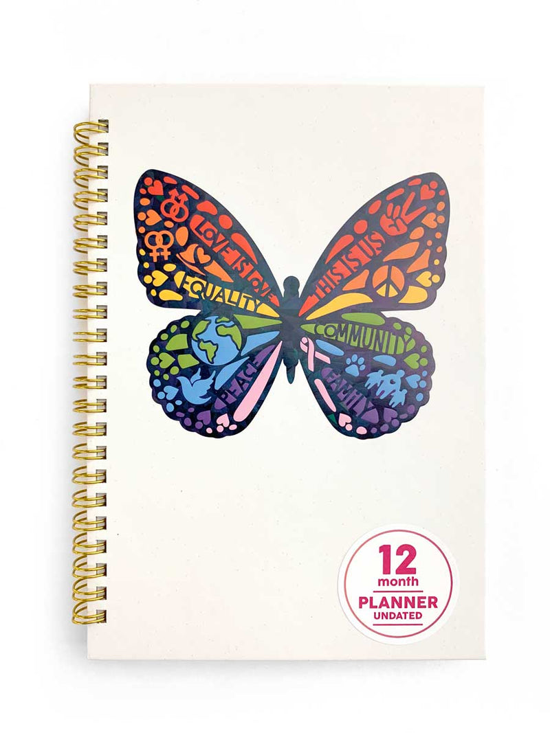 weekly planner featuring a colorful illustrated butterfly with positive sentiments on a white cover with gold spiral, shown on white background.