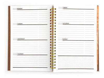 weekly spread of a weekly planner shown open with gold spine, shown on white background.