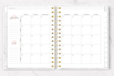 Undated planner shown open to a light pink, gray and white monthly page spread.