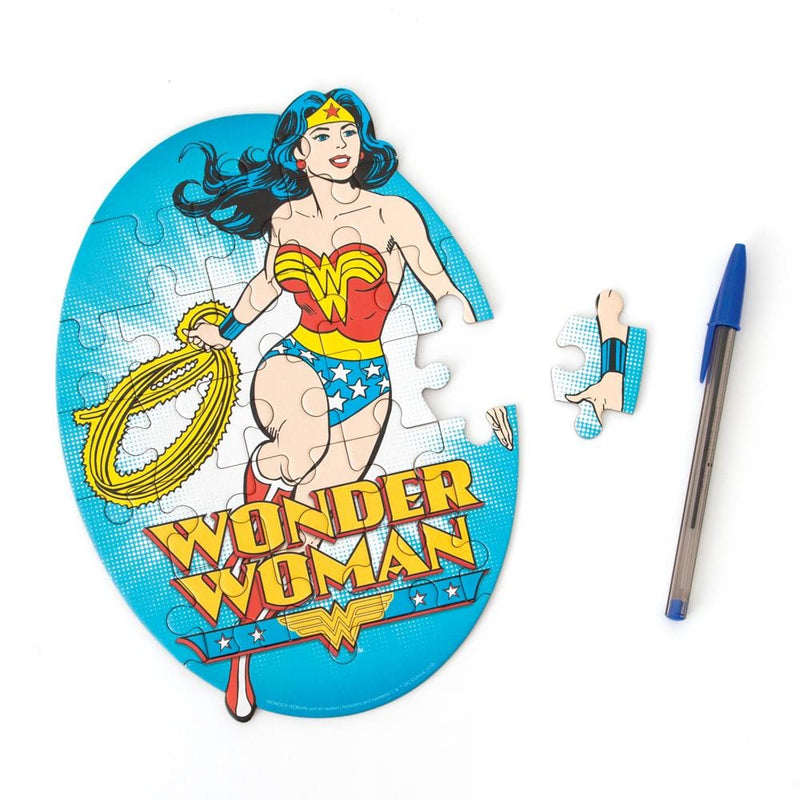 mini die cut jigsaw puzzle featuring wonder woman on a bright blue background, shown with pen and one separate piece on a white background.