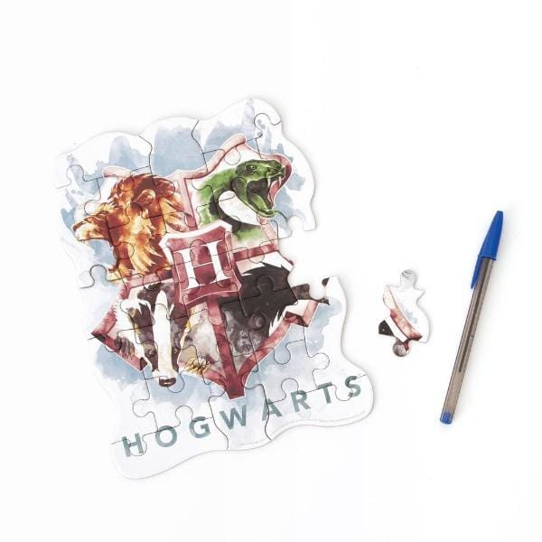 die cut mini jigsaw puzzle featuring Harry Potter™ Hogwarts crest, shown with pen and one separate piece on white background.