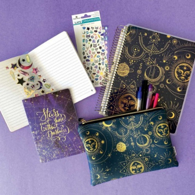 celestial pencil pouch, undated planner, stickers and notebook are displayed on a purple background with an assortment of pens.