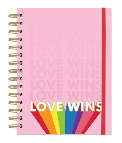 pink spiral notebook featuring LOVE WINS and rainbow with red elastic band shown on white background.
