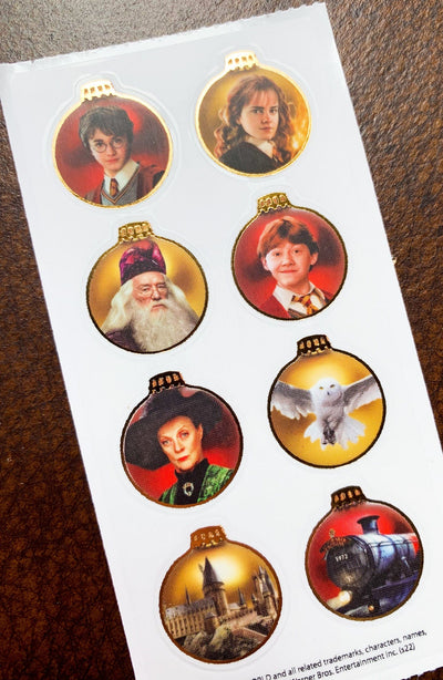 Single sheet of Harry Potter stickers featuring Harry Potter characters inside gold Christmas ornaments, shown on a white background.