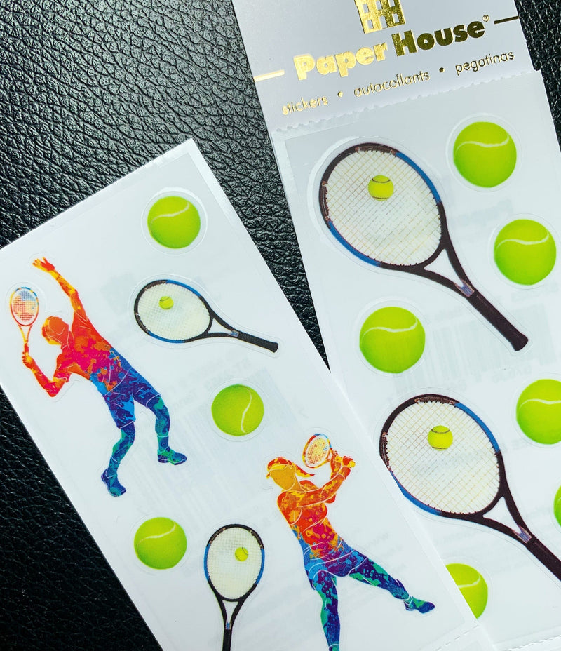 close up of stickers featuring colorful tennis players, racquets and balls, shown with package on black leather background.