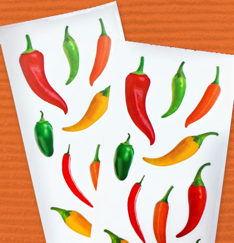 close up of 2 sheets of stickers featuring colorful hot peppers, shown on orange background.