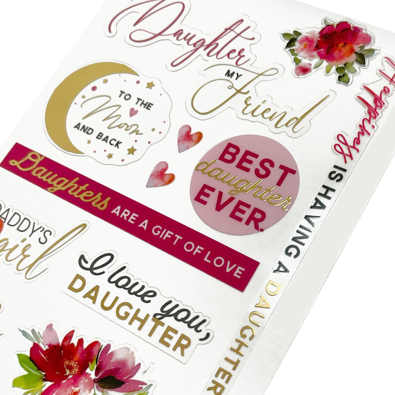 This image of scrapbook stickers shows the daugher themed sticker sheet on an angle featuring sentiments of love with pink and gold details.