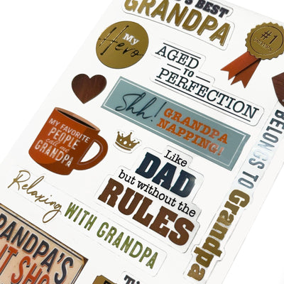This image of scrapbook stickers shows the grandpa themed sticker sheet on an angle featuring sentiments of love with blue and gold details.