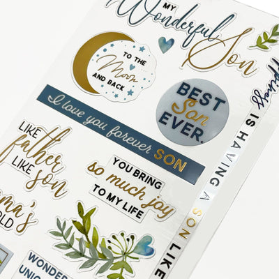 This image of scrapbook stickers shows the son themed sticker sheet on an angle featuring sentiments of love with blue and gold details.