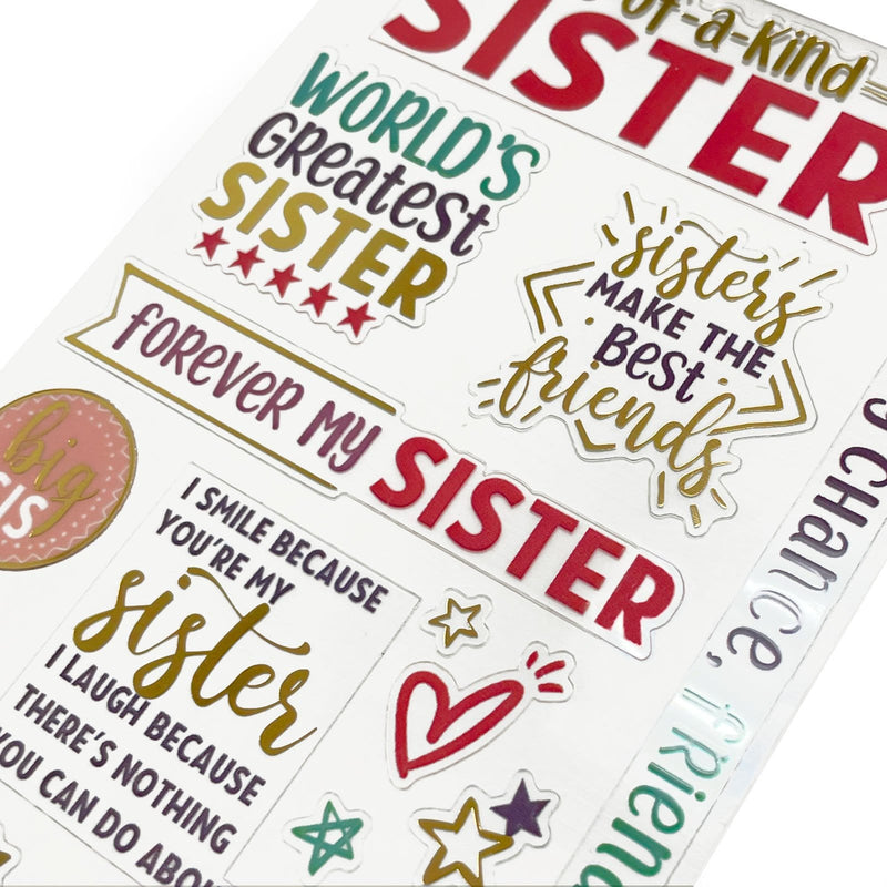 This image of scrapbook stickers shows the sister themed sticker sheet on an angle featuring sentiments of love with red and gold details.