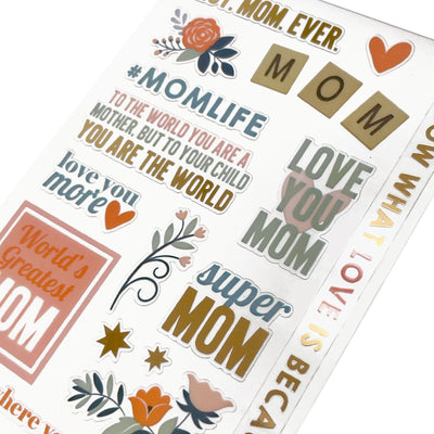 This image of scrapbook stickers shows the mom themed sticker sheet on an angle featuring sentiments of love with orange and gold details.