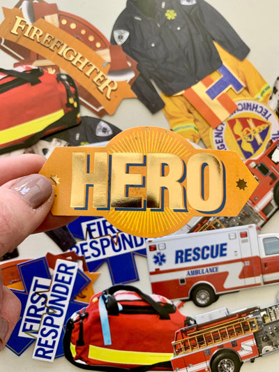 hand displays a close up of a gold foil HERO sticker with an assortment of more hero stickers.