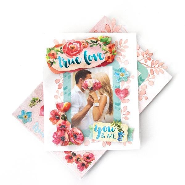 3D scrapbook stickers frame featuring a photo of a couple surrounded by colorful florals and hearts shown above a sheet of stickers on a white background.