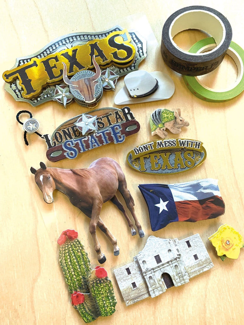 3D scrapbook stickers featuring Texas, the Alamo, a horse and cowboy hat shown next to 2 rolls of washi tape on a wood surface.