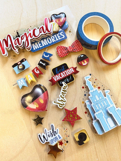 3D scrapbook stickers featuring colorful illustrations of a magical castle, a red polka dot bow tie, stars and balloons shown next to 2 rolls of washi tape on a wood surface.