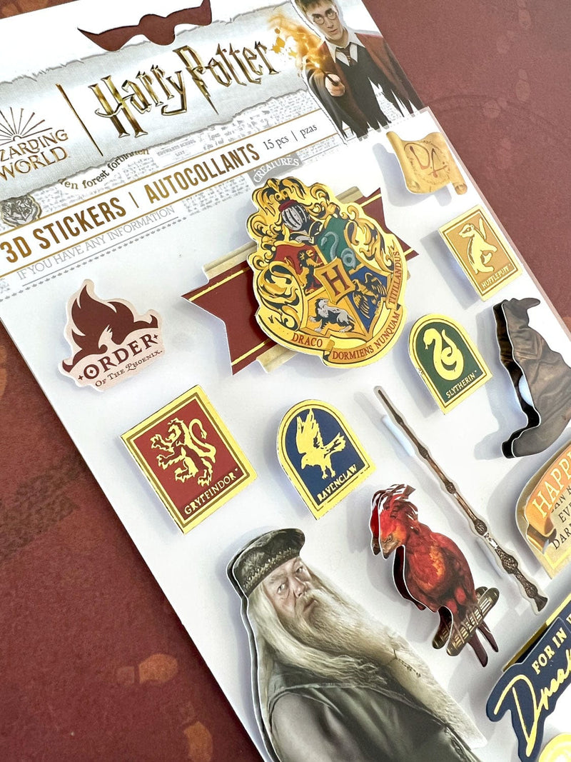 close up of Harry Potter stickers featuring Dumbledore and house crests, shown in package on dark red background.