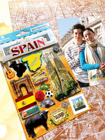 3D scrapbook stickers featuring Spain imagery including a bull, guitar and soccer ball shown next to a photo of a couple.