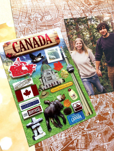 scrapbook stickers featuring photo real Canadian flag and moose shown next to a photo of a couple in the forest on a background of patterned paper.