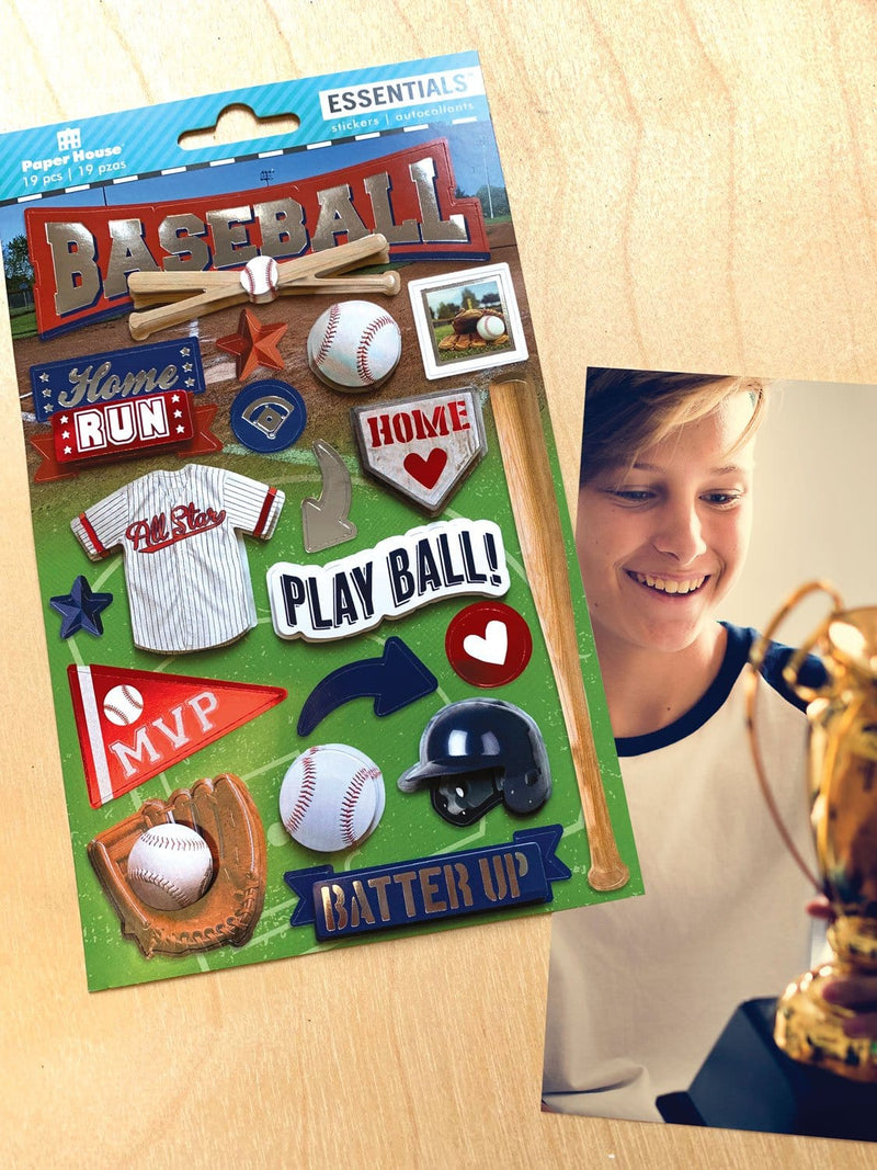 scrapbook stickers featuring baseball is shown next to a photo of a child and a trophy on a wood surface.