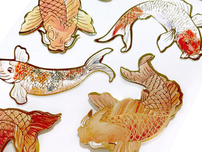 Close up of scrapbook stickers featuring orange and gold koi fish.