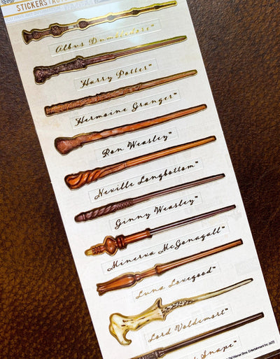 close up of Harry Potter stickers featuring 10 wands and their names shown in package, displayed on brown leather background.