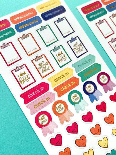 close up of of colorful planner stickers featuring mental health trackers, shown on teal background.