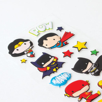close up of puffy stickers featuring Justice League chibi characters, shown on an angle on white surface.