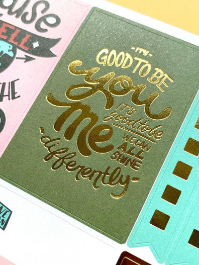 close up of planner sticker featuring diversity sentiment in gold lettering on green background