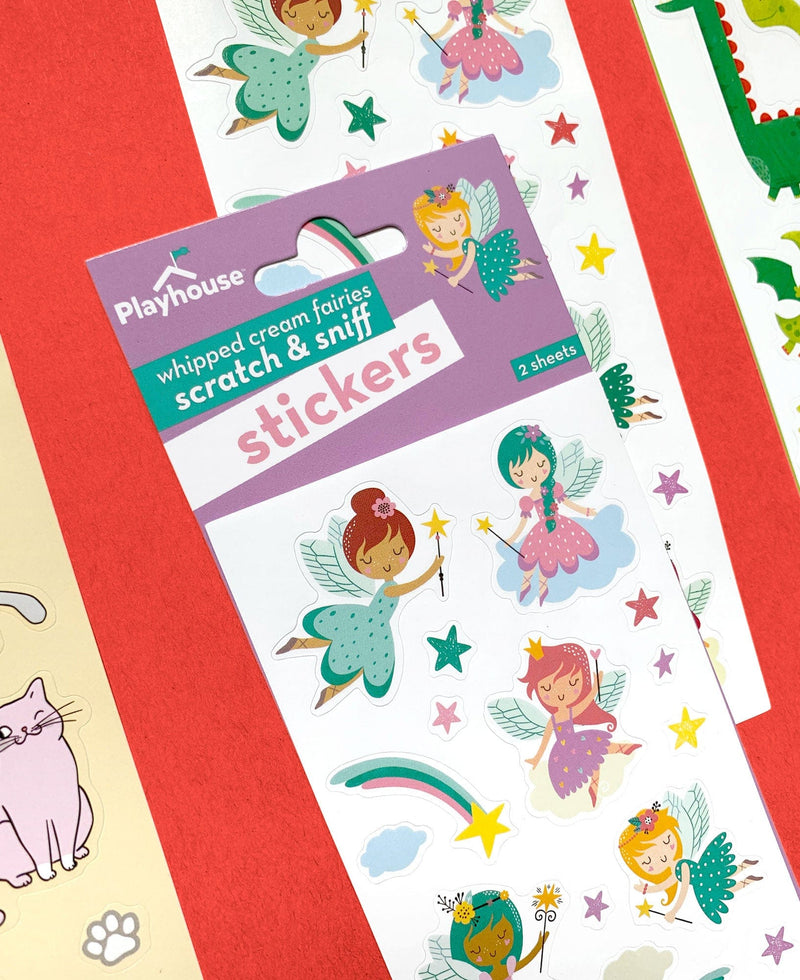 close up of scratch and sniff stickers featuring illustrated pastel fairies and stars shown in package on red background with other sheets of stickers.