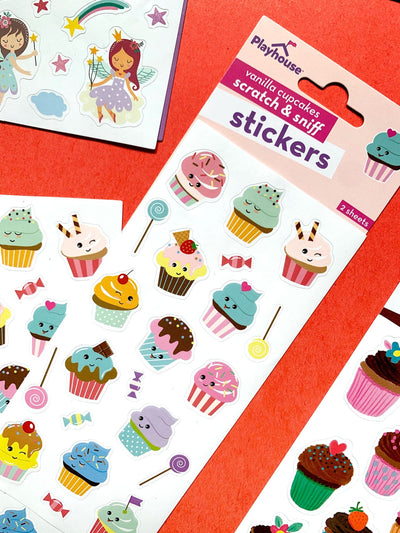 close up of scratch and sniff stickers featuring illustrated cupcakes and lollipops, shown on red background with other stickers.