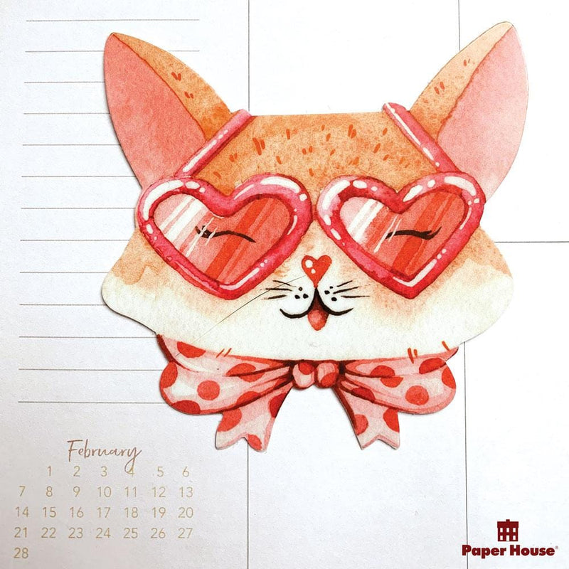 Shaped laptop sticker featuring a pink illustrated cat with a bowtie and glasses, is shown on a white planner spread with the month of February shown.