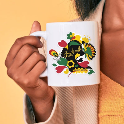 Shaped, vinyl sticker featuring black, red, yellow and green hearts and florals with the words Juneteenth 1865 in yellow shown on a white mug held by a woman of color.