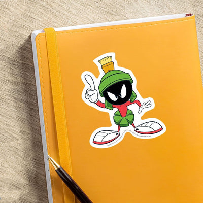 vinyl laptop sticker featuring a diecut Marvin the Martian shown adhered to orange notebook with pen.