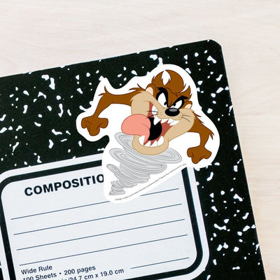 vinyl laptop sticker featuring a diecut Tasmanian Devil adhered to the front of a black and white composition notebook.