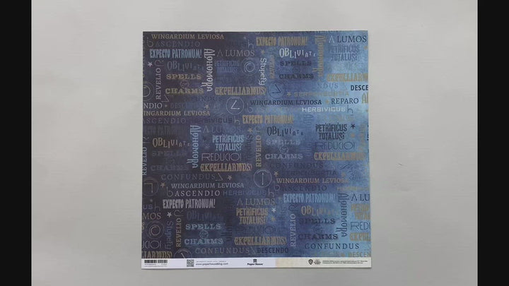 Female hands pick up harry potter scrapbook paper featuring text depicting spells like "Alohomora" and "Lumos" on one side with the swish &amp; flick wand motions in beige on the reverse.