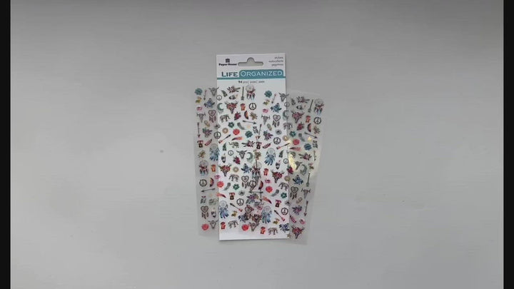 Female hands pick up and show front and back details of mini stickers featuring dream catchers, feathers and directional arrows.