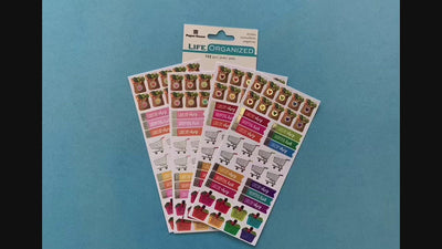 female hands display 4 sheets of planner stickers featuring colorful grocery functional stickers, on blue background with package.