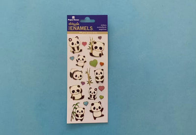 female hands displaying foil stickers featuring illustrated panda bears, bamboo, and hearts with gold details, on blue background with package.