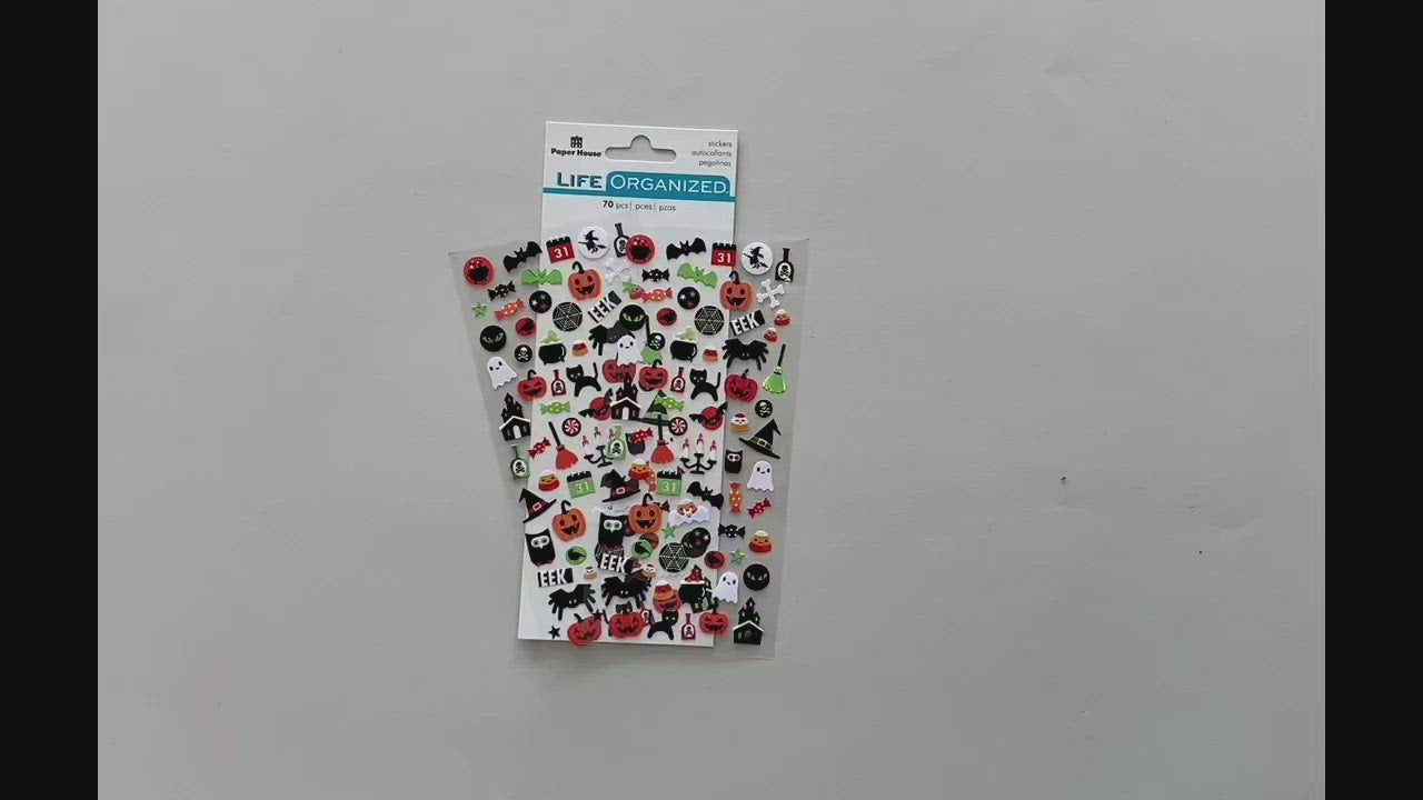 Female hands pick up and show in detail front and back of mini stickers featuring halloween cats, spiders, and pumpkins.